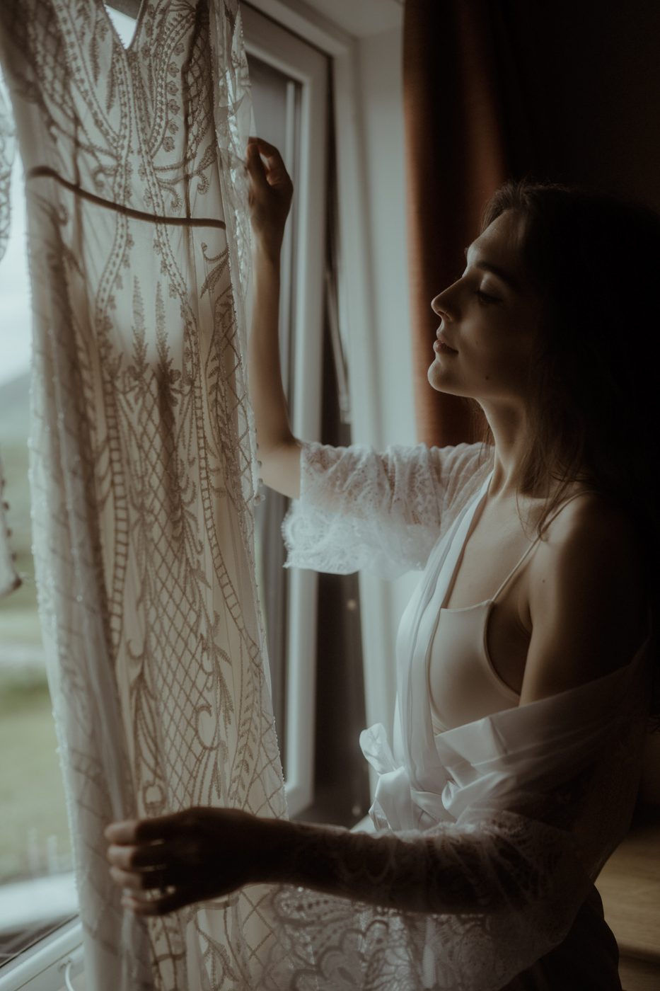 Bride by a lace-curtained window in soft light