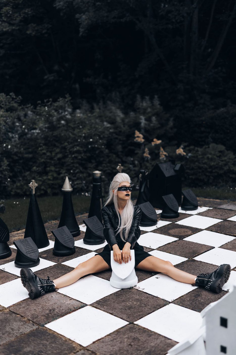 Seated on a giant outdoor chessboard in a white dress